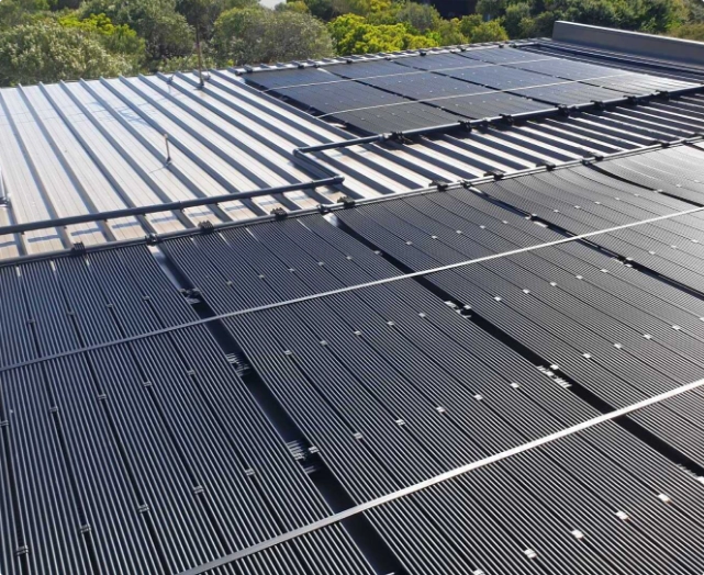 Rhino Platinum Rigid Solar Panels on a Light Grey Roof with Trees in Background